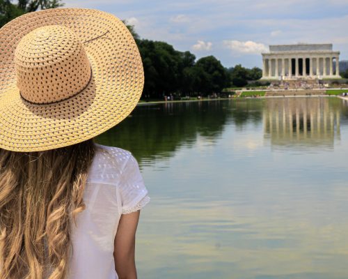A girl with a hat from behind looking at the Lincoln memorial